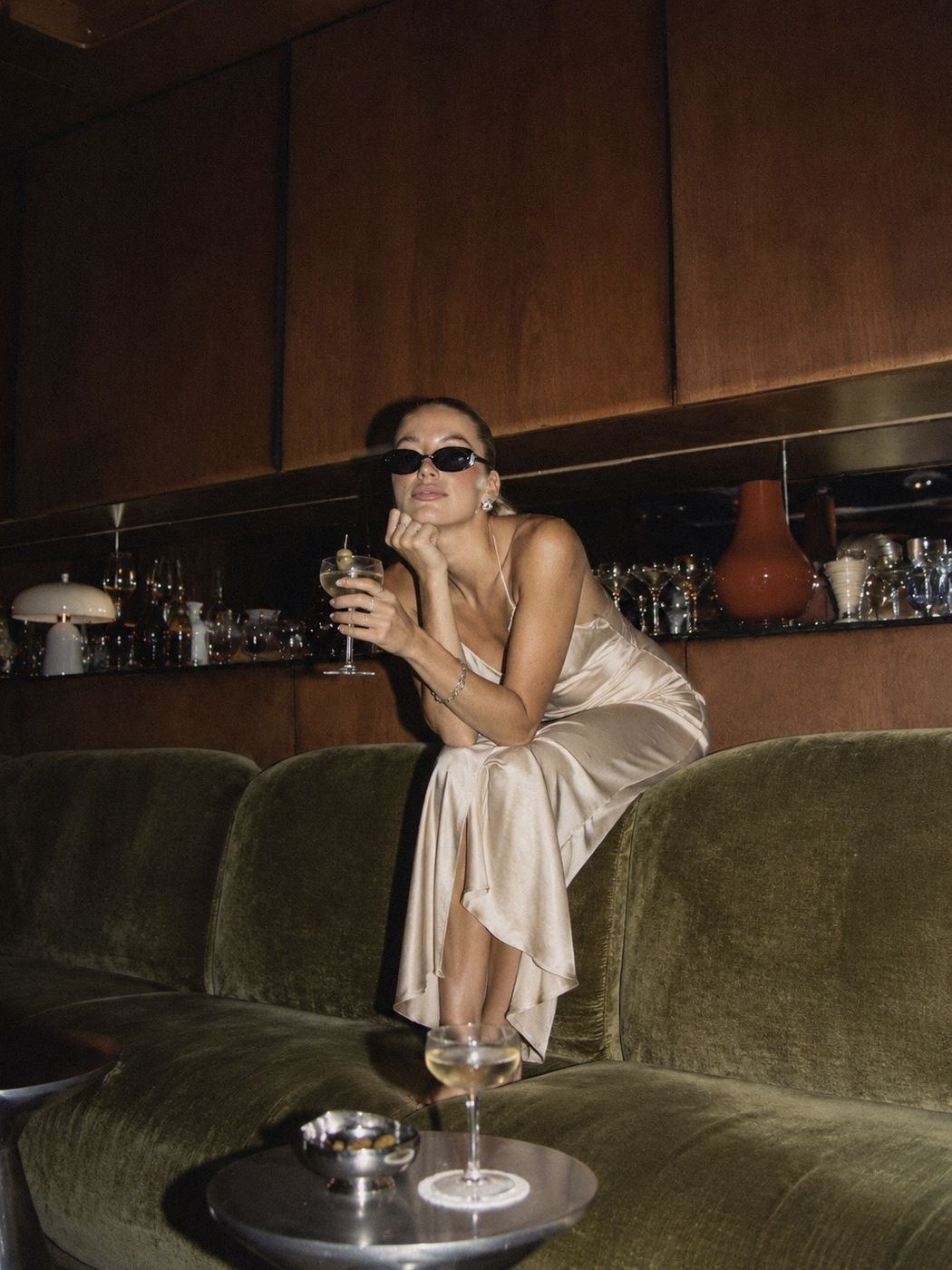 A guest on a green velvet sofa in a wood-panelled bar